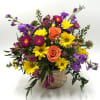A mix of fresh, seasonal blooms designed in a handled wicker basket.