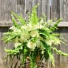 Large white rose and hydrangea arrangement with ferns in a gold urn on a metal stand
