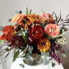 Mixed bouquet of roses, ranunculus, and chrysanthemums in a glass vase