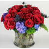 Red roses and blue hydrangeas in a clear glass vase