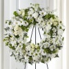 White floral wreath on a black stand with daisies and roses