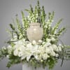 White floral arrangement with lilies and roses around a stone urn