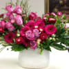 Pink roses and magenta daisies arranged in a white vase