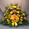 Large floral spray with yellow and peach flowers and a yellow ribbon