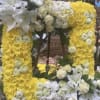 Yellow floral wreath with white lilies and roses on a stand