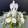 White angel figurine surrounded by white roses and greenery