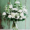 White roses and daisies arranged in a clear glass vase