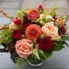 Mixed bouquet of roses, dahlias, and tulips in a glass vase
