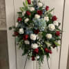 Standing floral spray with red roses, white carnations, and blue flowers