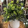 Green floral arrangement in a white ceramic pot