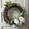 White floral wreath on a grapevine ring with green accents