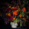 Bouquet of orange and burgundy flowers in a white skull vase