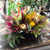 Mixed floral arrangement with orchids, roses, and bright tropical blooms in a dark container