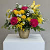 Bright mixed flower arrangement in a gold vase with a yellow butterfly accent.