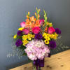 Colorful mixed bouquet in a glass vase with pink hydrangea and orange gladiolus