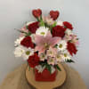 Bouquet of red roses, pink lilies, and white daisies in a red vase with heart picks