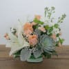 Peach roses and white lilies in a glass vase with a succulent