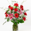 Red roses and pink lilies in a clear glass vase