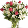 Pink tulips and white flowers arranged in a clear glass vase
