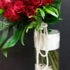 Red roses in a tall glass vase with white bead strands
