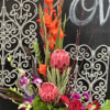 Tall tropical floral arrangement with red protea and orange blooms