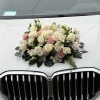 Cream and pink floral arrangement mounted on the hood of a white BMW.