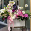 Pink and white floral arrangement in a white box with a ribbon