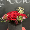 Red roses arranged in a black vase with a gold "Love" topper.