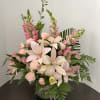 Pink lilies and roses arranged in a glass vase