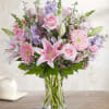 Pink roses and lilies arranged in a clear glass vase