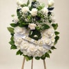 White rose and chrysanthemum wreath on an easel with a ribbon