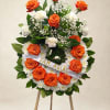 Orange roses and white flowers arranged on a standing easel wreath
