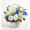 White lilies, roses, and blue flowers in a white wicker basket