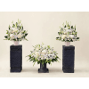 Three white floral arrangements in dark pedestal vases