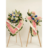 Two pink and white floral funeral wreaths on wooden easels