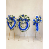 Three blue and white floral funeral wreaths on wooden stands