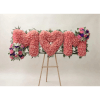 Pink floral heart-shaped arrangement on an easel with small bouquet clusters