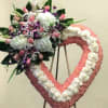 Heart-shaped floral wreath with pink and white flowers and a mixed bouquet on the left