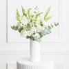 White roses and snapdragons in a tall white vase