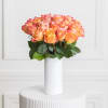 Orange and pink roses arranged in a white vase