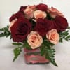 Bouquet of red and peach roses in a square glass vase with pink ribbon
