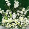 White floral basket with lilies, daisies, and an angel figurine
