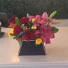 Mixed bouquet with pink lilies, red roses, and yellow spray roses in a black box