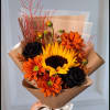 Bouquet with a sunflower, orange daisies, and black roses in brown wrap