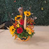 Halloween pumpkin container with sunflowers, roses, and a small fox figurine