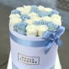 White signature box full of white and baby blue roses. 