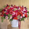 Large pink and orange floral arrangement in a white vase