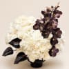 White rose arrangement with dark purple orchids in a black vase