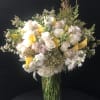 Bouquet of white and pale pink roses with yellow calla lilies in a glass vase