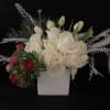 White roses and tulips in a white square vase with red blooms at one side